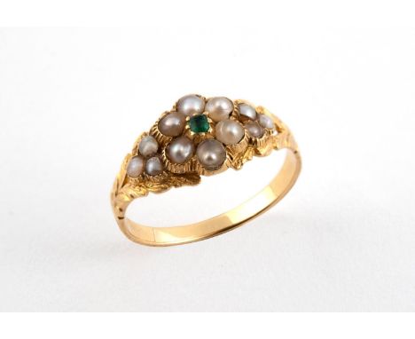 A VICTORIAN EMERALD AND PEARL MOURNING RING of flowerhead form, centred with a small emerald within a surround of half pearls