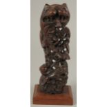 A CARVED AND PIERCED WOOD ORNAMENTAL FIGURE, mounted to a wooden base, 24.5cm high.