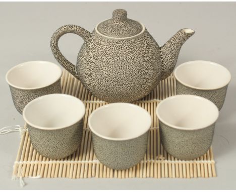 A JAPANESE SPECKLE-GLAZED CERAMIC TEA SET; comprising a teapot and five cups, (6).