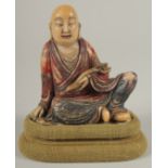 A CHINESE CARVED HARDSTONE FIGURE OF LUOHAN, holding ruyi scepter, with fabric overlaid stand and