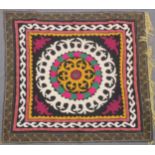 AN UZBEK SUZANI EMBROIDERED TEXTILE, with central foliate motif in yellow, green, maroon, black, and