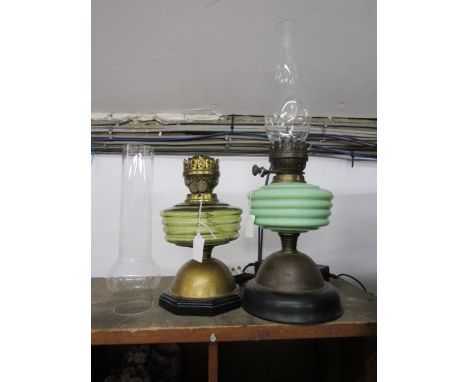 A yellow and a green glass brass based oil lamp