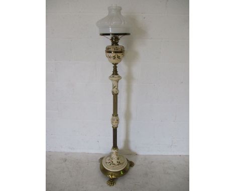 An adjustable floor standing pottery and brass oil lamp with claw feet, the pottery sections decorated with mistletoe