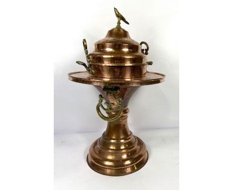 A large copper and brass Islamic incense burner, late 19th or early 20th century, with a pierced domed lid, bird finial, the 