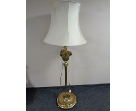A brass standard lamp with cast rams head and acanthus leaf detail, with shade  