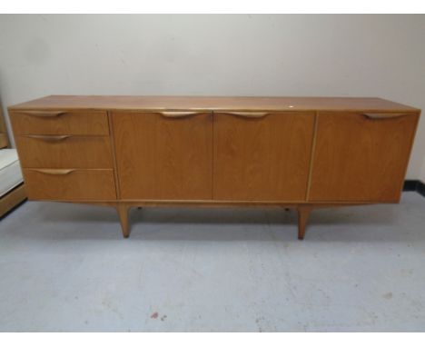 A mid 20th century teak Mcintosh furniture triple door cocktail sideboard fitted three drawers on raised legs.