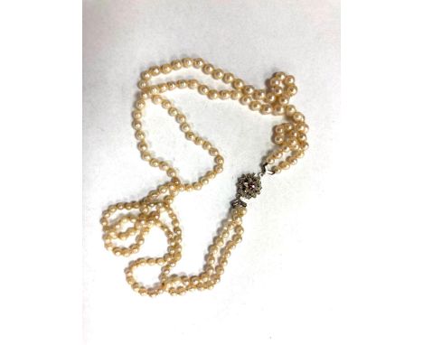 A double strap of pearls on white gold clasp set with a ruby 