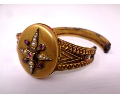 A Victorian pinchbeck bangle with central locket set with seed pearls and ruby-coloured stones (for spares and repairs)