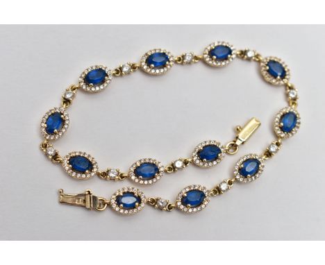 A YELLOW METAL GEM SET BRACELET, comprised of twelve oval cut synthetic blue spinel, each set with a surround of circular cut