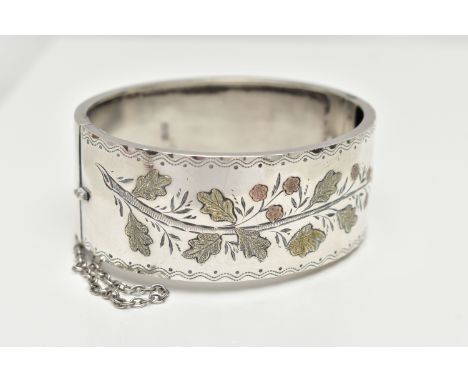 A SILVER HINGED BANGLE,  a wide bangle decorated with a yellow and rose metal foliage etched pattern, approximate width 25mm,