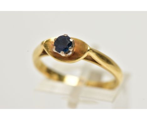 A YELLOW METAL SINGLE STONE RING, designed with a six claw set, circular cut blue sapphire, within a polished dish surround, 