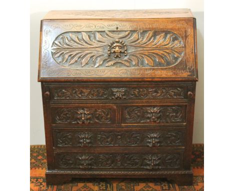 Victorian Flemish-style profusely-carved oak bureau, the sloped front with lion mask roundel enclosing a fitted interior abov