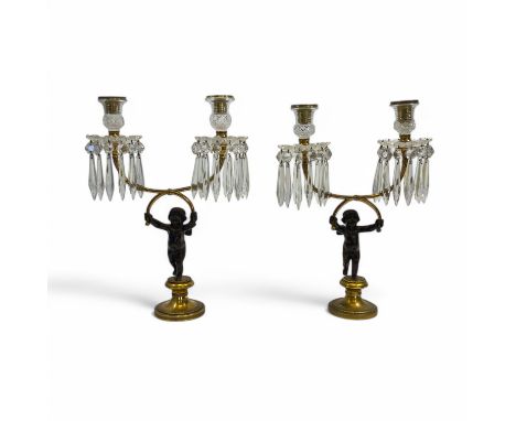 A pair of Regency style gilt and patinated bronze twin branch candelabra, each sconce sleeved with hobnail cut glass, over lo