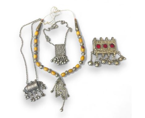 A collection of white metal Bedouin jewellery. Comprising a&nbsp; glass panel set amulet, an amber type bead necklace and two