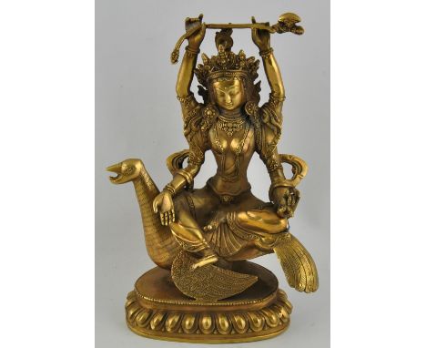 A Sino-Tibetan statue of a multi armed Buddhist diety holding an axe and seated upon a mythical bird, H27cm