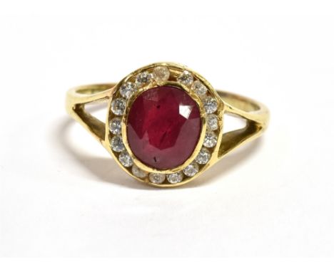 A 14CT GOLD RUBY AND WHITE CLUSTER RING  (Note: The oval cut ruby 7mm x 5mm glass filled treated), split shoulder to yellow g