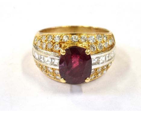 A RUBY AND DIAMOND SET 18CT GOLD RING The central cushion cut ruby weighing approx.  3 carats, four claw set to a central cha