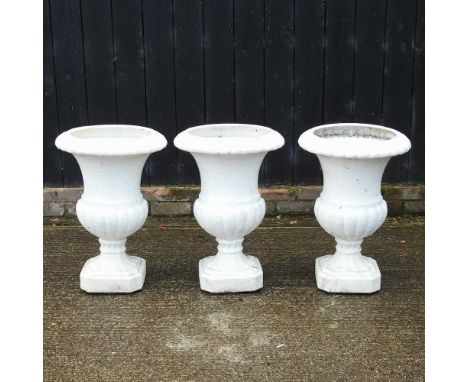 A set of three white painted composition garden urns, of fluted pedestal shapeEach 68cm high