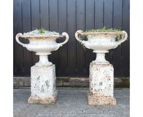 A pair of large white painted cast iron garden urns, 19th century, each of twin handled form, on a pedestal base, 90cm high o