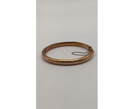 A 9ct rose gold hinged bangle having floral engraved decoration, 10.7g Location: 