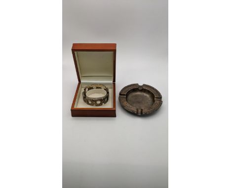 An Adie Bros silver ashtray having decorative boarder, hallmarked Birmingham 1961, together with a silver hinged bangle, tota