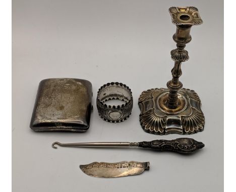 Silver items to include a candlestick, a knife blade, a cigarette case, a silver handled button hook and a white metal napkin