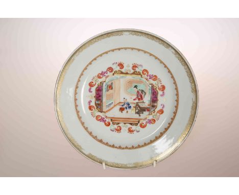 A CHINESE EXPORT PLATE, enamel painted with two figures and a dog in an interior, within iron red and gilt borders. 23cm