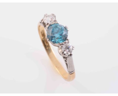 A BLUE ZIRCON AND DIAMOND RING, the round cut claw set blue zircon set between two brilliant cut claw set diamonds, all set i