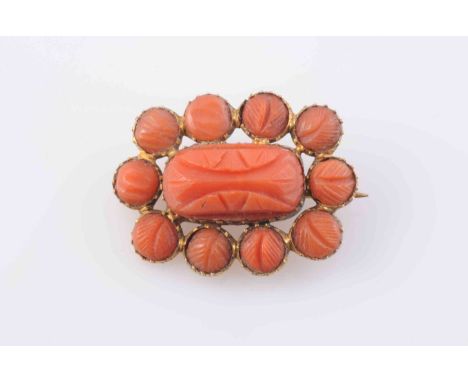 A CORAL BROOCH, circa 1880, the central rectangular carved coral plaque set within a surround of ten circular carved coral pl