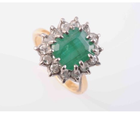 AN EMERALD AND DIAMOND RING, the square cut emerald fourteen claw set raised within a surround of fourteen brilliant cut claw