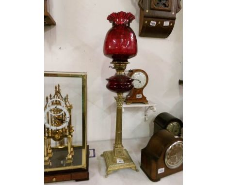 A brass Corinthian column oil lamp with ruby glass font and shade