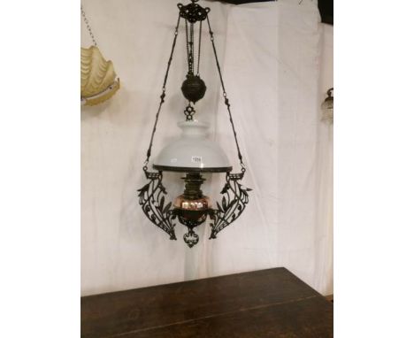 An Art Nouveau cast iron rise and fall oil lamp with brass font and original shade