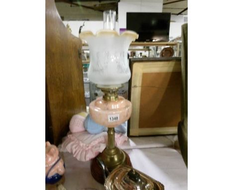 A Victorian oil lamp with brass column and mottled peach glass font