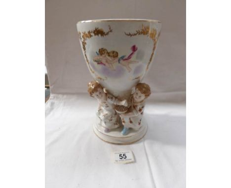A porcelain pot (possibly oil lamp base) supported by 4 children, decorated with cherubs and with a blue crossed sword mark o