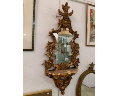 A gilt framed mirror with shelf