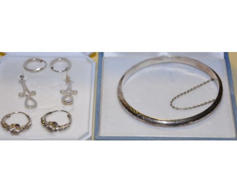 An engraved silver bangle together with three pairs of assorted silver hoop and pendant earrings
