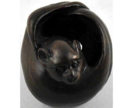 A hardwood netsuke, modelled as a rat within a seed pod, signed, L 4cm.