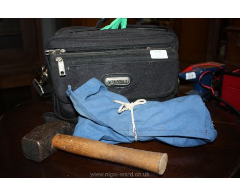 A black soft tool Bag containing camping equipment including a tent peg lifting key, tent pegs and a lump hammer.   
