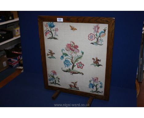 A wooden framed fire screen with embroidered panel.