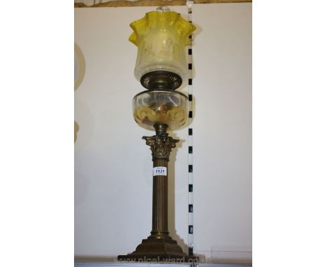 A brass columned oil lamp with yellow and white shade.