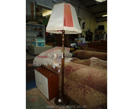 An Oak turned pillar Standard Lamp having a fringed cream and terracotta coloured parchment type shade. 64'' high approx.