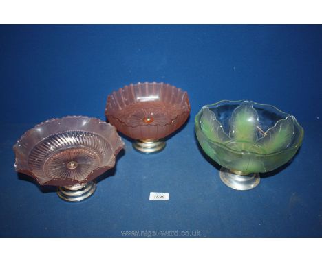 Three vintage bowls on stands; one green and two pink.
