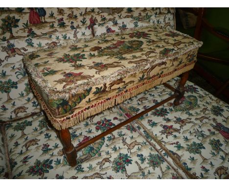 An Ercol long Footstool on turned legs with perimeter stretchers and upholstered in Sanderson's Hog Hunting landscape scene f