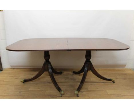 Regency style mahogany twin pedestal extending dining table, the rounded rectangular top with reeded edge on vase shaped colu