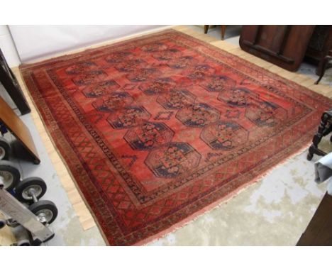 Large Pakistani Tekke carpet with three rows of seven quartered guls in multiple borders on blood red ground, 328 x 268cm