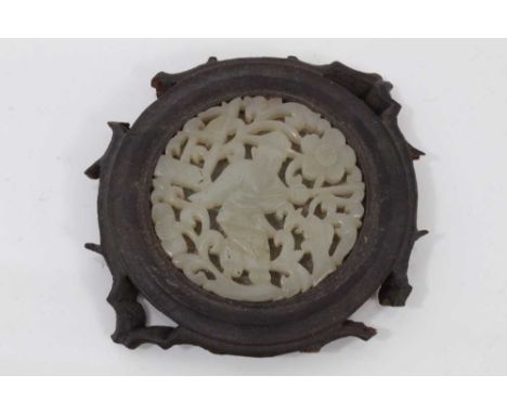 Chinese jade plaque, carved and pierced with a fisherman and scrolling foliage, in a wooden mount, 8cm across
