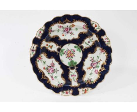 A Worcester plate, circa 1770, painted with flowers, on a blue scale ground, pseudo-Chinese seal mark to base along with John