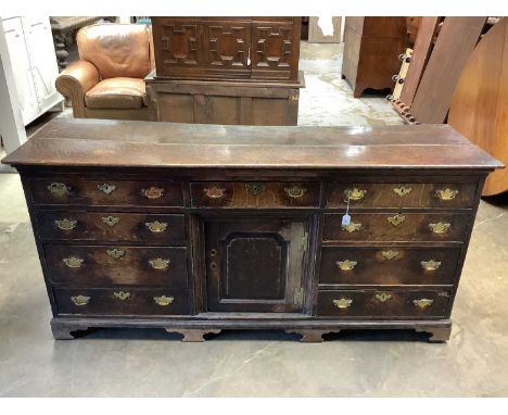 18th century and later oak dresser base,with central fielded panel cupboard and nine drawers, raised on cabriole legs, 195cm 