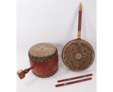 Two antique highly decorative Chinese drums, the first with long handle, 64cm long, the other of traditional form with squat 