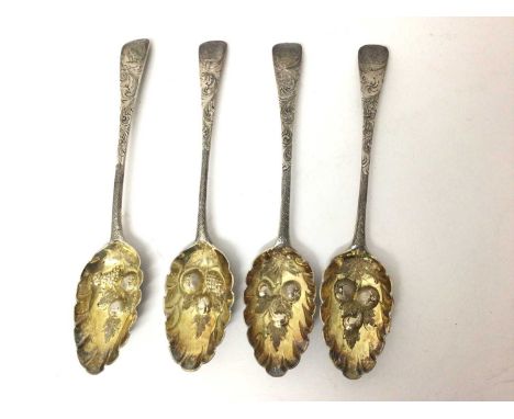 Four Georgian silver berry spoons with embossed and gilded scalloped bowls, chased handles and engraved family crests. Dates 